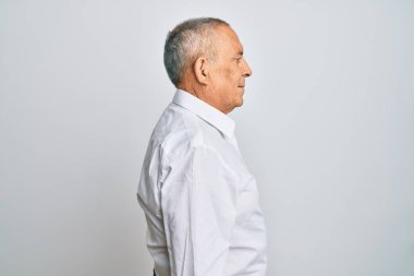 Yakışıklı, beyaz gömlek giyen, rahat bir görünüm takınan, doğal yüzlü ve kendine güvenen bir gülümseme takınan bir adam.. 