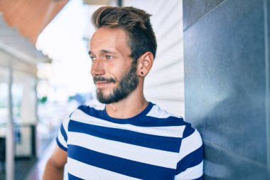 Sakallı yakışıklı beyaz adam, dışarıda mutlu bir şekilde gülümsüyor.