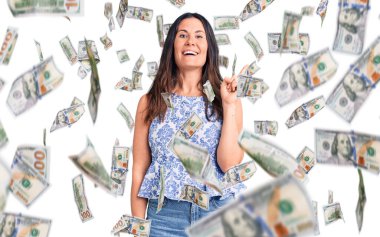 Genç, güzel, esmer, sıradan tişörtler giyen, yüzünde kocaman bir gülümseme olan, eli ve parmağı kameraya bakan bir kadın..