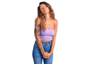 Young hispanic woman with tattoo wearing casual clothes looking at the camera blowing a kiss on air being lovely and sexy. love expression. 