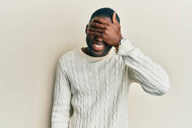 Sıradan kıyafetler giyen, gülümseyen ve gülen genç Afro-Amerikan erkeği şaşırtmak için gözlerini kapatıyor. kör kavram. 