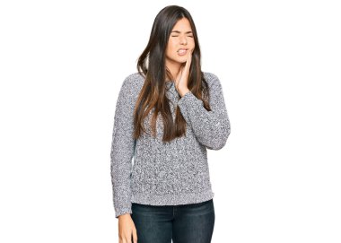 Genç esmer kadın diş ağrısı ya da diş hastalığından dolayı sıradan bir kazak giyip ağızlarına acı dolu bir ifadeyle dokunuyor. dişçi 