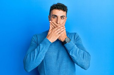 Sıradan bir kazak giyen İspanyol genç adam yanlışlıkla elleriyle ağzını kapatırken şok oldu. gizli kavram. 