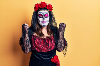 Sarı üzerine ölü kostümü giymiş genç bir kadın kollarını kaldırarak ve açık gözlerle başarıyı kutluyor ve şaşırıyor. Kazanan konsept. 