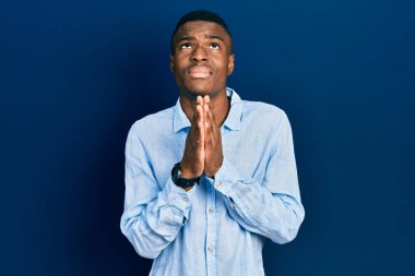 Genç Afro-Amerikalı bir adam günlük giysiler giyip elleri bağlı yalvarıyor ve dua ediyor. Yüzünde umut ifadesi var. Çok duygusal ve endişeli. Yalvarıyor. 