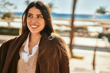 Genç İspanyol kadın gülümseyerek şehirde mutlu mesut dikiliyor..