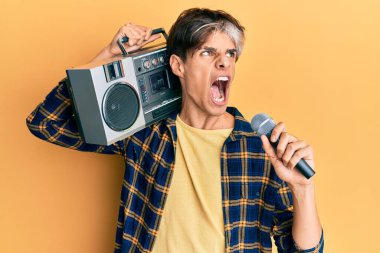 Genç İspanyol adam mikrofon ve teyp kullanarak şarkı söylüyor kızgın ve öfkeli çığlıklar atıyor öfkeyle bağırıyor. öfke ve agresif konsept. 