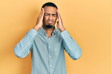 Genç Afro-Amerikan adam gündelik kıyafetler giyiyor. Baş ağrısı çekiyor, çaresiz ve stresli. Çünkü acı ve migren ağrısı var. Eller başının üstünde.. 
