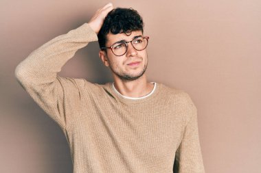 Gündelik kıyafet ve gözlük takan genç İspanyol adam soru sorup kafasını karıştırıyor. Şüpheyle kararsız, kafa kafaya düşünerek. Düşünceli kavram. 