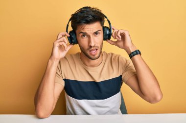 Genç yakışıklı adam kulaklık takıp müzik dinliyor. Şok olmuş, şüpheci ve alaycı görünüyor. Ağzını açtığında şaşırıyor. 