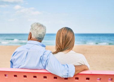 Orta yaşlı İspanyol bir çift sahilde bankta oturuyor..