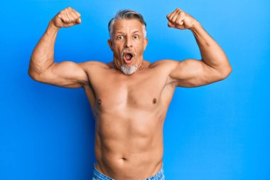 Orta yaşlı, gri saçlı, üstsüz bir adam spor yapıyor. Korkmuş ve şok olmuş bir halde. İfade, korku ve heyecanlı bir yüz ifadesi.. 