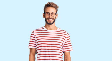 Sakallı, sıradan kıyafetler giyen, mutlu ve havalı bir gülümsemesi olan yakışıklı sarışın bir adam. şanslı kişi. 