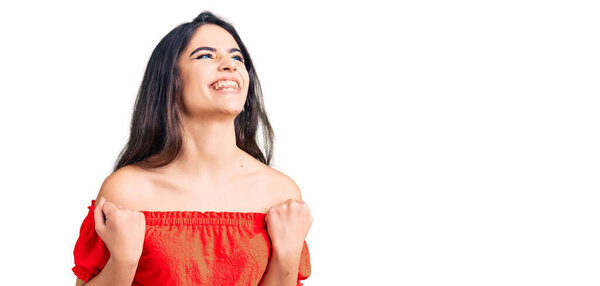 Брюнетка девушка-подросток в повседневной одежде взволнована успехом с поднятыми руками и закрытыми глазами, празднуя победу улыбаясь. победитель концепция. 