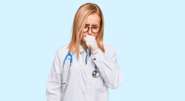 Doktor üniforması ve steteskop giyen güzel beyaz kadın kendini iyi hissetmiyor ve soğuk algınlığı veya bronşitin belirtisi olarak öksürüyor. sağlık hizmeti kavramı. 