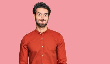 Günlük kıyafetler giyen genç İspanyol adam komik yüzlü yanakları şişiriyor. Havayla şişmiş ağız, çılgın bir ifade.. 