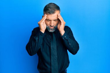 Stres yüzünden orta yaşlı yakışıklı bir adam iş gömleği giyiyor ve eli başının üstünde kravat takıyor. migren ağrısı. 