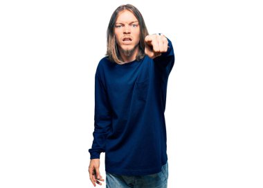 Uzun saçlı yakışıklı beyaz adam, sıradan bir süveter giyiyor. Kameraya kızgın ve sinirli bir şekilde bakıyor. 