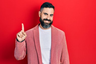 Bir fikir ya da soruyla gülümseyen iş kıyafetleri içindeki genç İspanyol adam mutlu bir yüzle işaret ediyor, bir numara. 