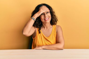 Orta yaşlı, sıradan kıyafetler giyen güzel bir kadın masada mutlu bir şekilde oturuyor ve gülümsüyor. arama kavramı. 