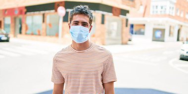 Coronavirus protencion tıbbi maske takan yakışıklı beyaz bir adam şehirde yürüyor..