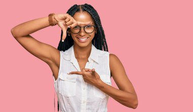 Beautiful hispanic woman wearing casual clothes and glasses smiling making frame with hands and fingers with happy face. creativity and photography concept. 