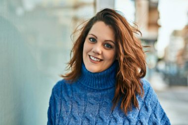 Genç İrlandalı artı cüsseli kız gülümseyerek şehirde mutlu mesut duruyor..