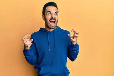 Gündelik kıyafetler giyen genç İspanyol adam deli gibi bağırıyor ve agresif bir ifade ve kollarla bağırıyor. hüsran kavramı. 