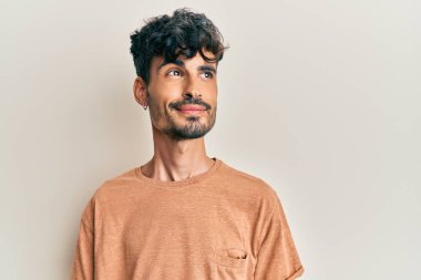 Gündelik kıyafetler giyen genç İspanyol adam gülümseyip yan tarafa bakıyor ve düşünüyor.. 