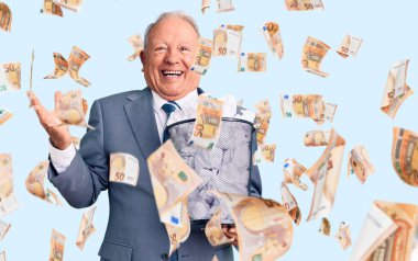 Kıdemli yakışıklı, gri saçlı, kağıt kutuyla buruşmuş belgeyle zafer kutlaması yapan mutlu bir gülümseme ve kaldırılmış ellerle kazanan bir ifade.