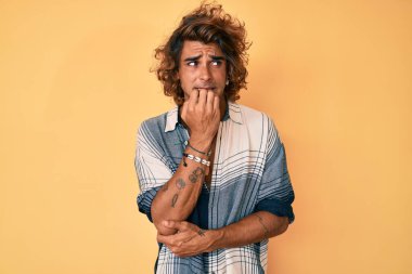 Yaz tarzı giyinen genç İspanyol adam gergin ve gergin görünüyor. Ağzı tırnak yiyen eller. anksiyete. 