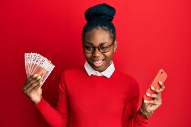 Genç Afrikalı Amerikalı kadın elinde Norveç Kronu banknotları tutarak kameraya seksi bir ifadeyle bakıyor, neşeli ve mutlu bir yüzle.. 