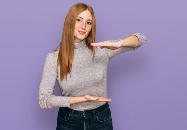 Genç İrlandalı kadın, sıradan kıyafetler giyiyor. Elleriyle işaret ediyor. Büyük ve büyük beden işareti, ölçü sembolü. Kameraya bakıp gülümsüyor. ölçüm kavramı. 