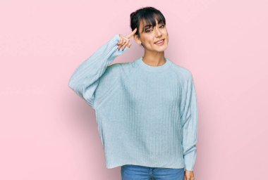 Gündelik kıyafetler giyen genç İspanyol kadın gülümseyerek tek parmağıyla kafasını işaret ediyor, harika bir fikir ya da düşünce, iyi bir hafıza. 