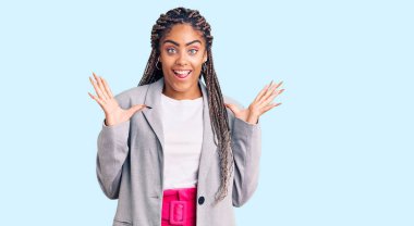 Örgülü, iş kıyafetleri giymiş genç Afro-Amerikalı kadın çılgın kutlamalar yapıyor ve kollarını kaldırıp heyecanla haykırarak başarıyı kutluyor. Kazanan konsept 