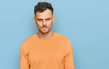 Gündelik kıyafetler giyen, kuşkucu ve gergin genç İspanyol bir adam sorun yüzünden surat asıyor. negatif kişi. 