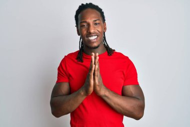Saçları örgülü Afro-Amerikan bir adam. Elleriyle dua ediyor. Affedilmeyi diliyor.. 