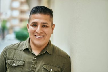 Genç Latin adam gülümseyerek şehirde mutlu mesut dikiliyor..