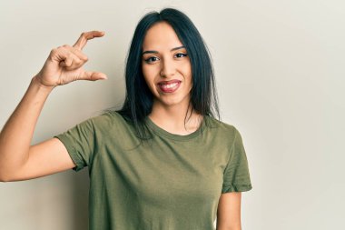 Gündelik tişört giyen, gülümseyen, kendine güvenen, el hareketi yapan, parmaklarıyla işaret yapan ve kameraya bakan genç İspanyol kız. ölçüm kavramı. 