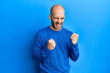 Gündelik kazak giyen genç İspanyol adam kolları havada ve gözleri kapalı olarak başarıyı kutluyor ve şaşırıyor. 