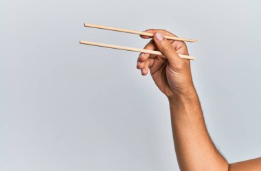 İzole edilmiş beyaz arka planda tahta çubuklar tutan İspanyol bir adamın eli..