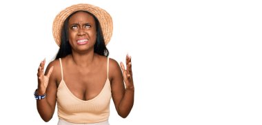 Genç siyahi kadın çılgın ve kızgın şapkalar takıyor ve agresif bir ifadeyle bağırıyor ve kollarını kaldırıyor. hüsran kavramı. 