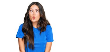 Güzel esmer, sıradan kıyafetler giyen, dudaklarıyla balık suratı yapan, çılgın ve komik bir jest yapan genç bir kadın. Komik ifade. 