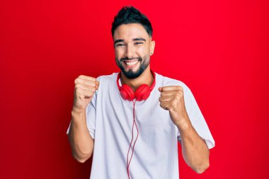 Sakallı genç adam müzik dinlerken kulaklık takıyor. Kolları havada, gözleri kapalı zafer kutlamaları yapıyor. Kazanan konsept. 