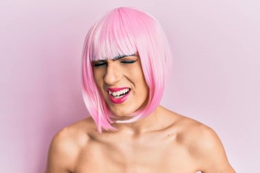 Mide bulantısı, acı verici bir hastalık yüzünden kadın makyajı yapan genç adam ellerini karnına koyup pembe peruk takıyor. Ağrı kavramı. 