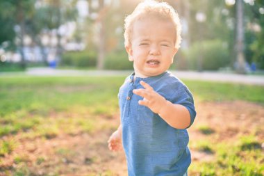 Güneşli bir günde parkta öfke nöbeti geçirirken ağlayan tatlı ve üzgün bir çocuk. Güzel sarı saçlı erkek çocuk dışarıda gözyaşları içinde hayal kırıklığına uğradı.
