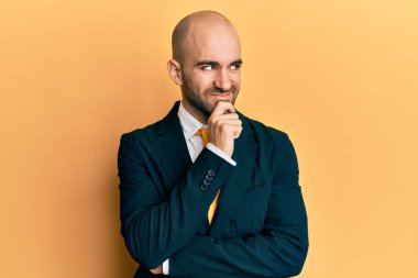 Genç İspanyol bir adam iş elbisesi giyiyor ve eli çenesinde kravat takıyor. Soru sormayı düşünüyor. Düşünceli bir ifade. Düşünceli bir yüzle gülümsüyor. şüphe kavramı. 