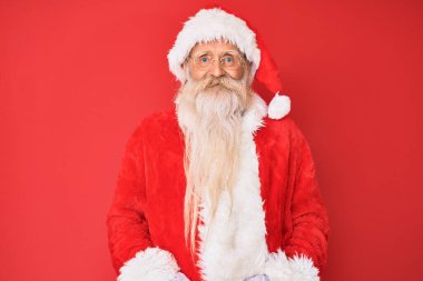 Gri saçlı, uzun sakallı, geleneksel Noel Baba kostümü giyen mutlu ve havalı bir gülümsemesi olan yaşlı bir ihtiyar. şanslı kişi. 