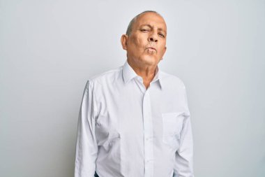 Handsome senior man wearing casual white shirt looking at the camera blowing a kiss on air being lovely and sexy. love expression. 