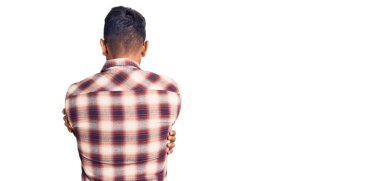 Gündelik kıyafetler ve gözlük takan genç İspanyol adam kendine sarılıyor, mutlu ve pozitif. Sevgi ve özgüven. 